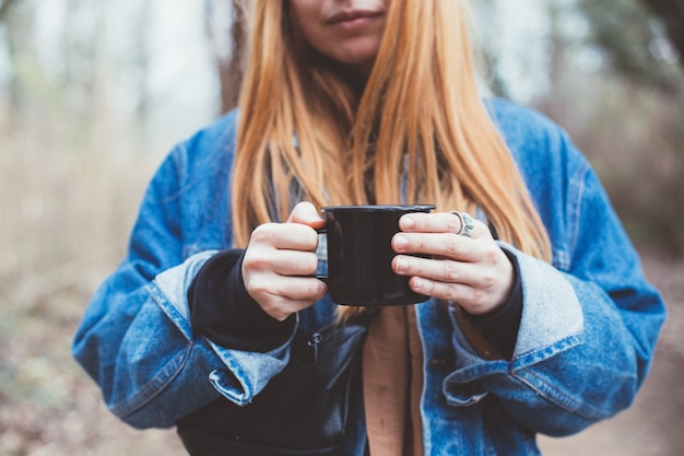 Young woman drinks coffee cup on lake shore