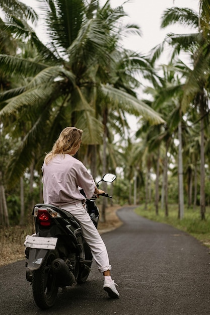 Бесплатное фото Молодая женщина за рулем мопеда тропическая жизнь