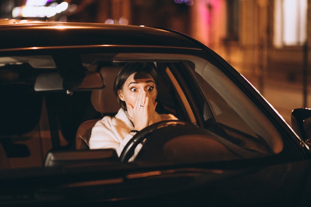 Молодая женщина за рулем в машине ночью