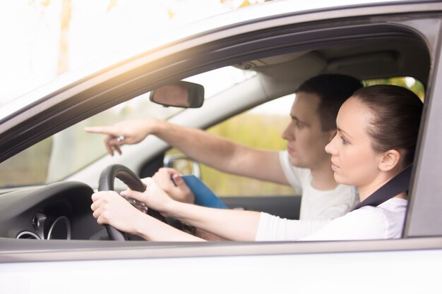 Young woman driving, man pointing the direction