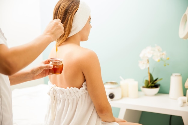 Free photo young woman during a hair removal session with honey at a beauty spa