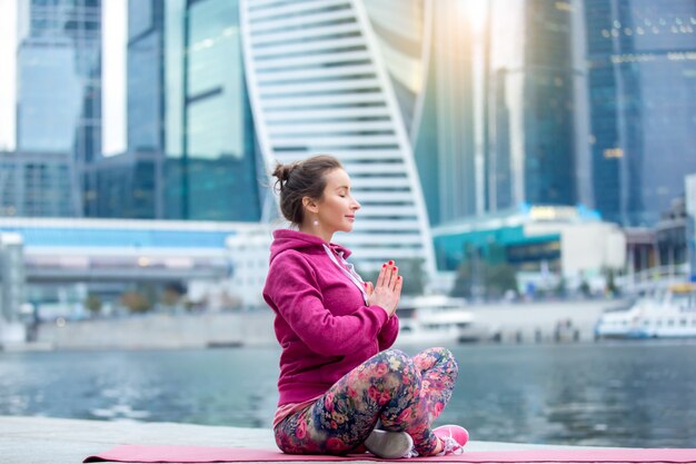 Young woman in Easy Seat pose against the city and river