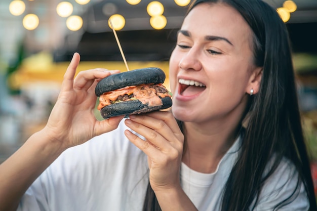 A young woman eating burger in street cafe – Free Stock Photo for Download