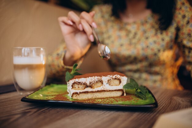 Young woman eating delicious tiramisu in a cafe