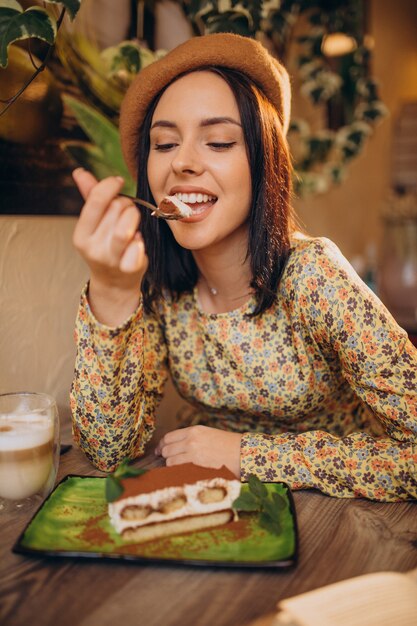 Young woman eating delicious tiramisu in a cafe