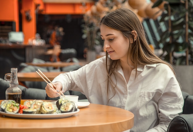 Foto gratuita giovane donna che mangia e che gode dei sushi freschi