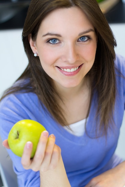 緑のリンゴを食べる若い女性。