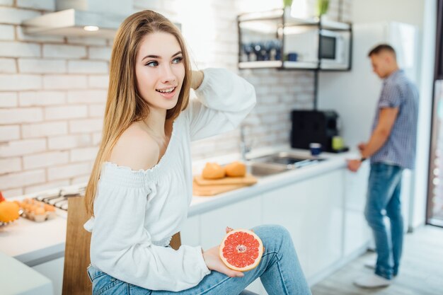 молодая женщина ест здоровый завтрак грейпфрут.