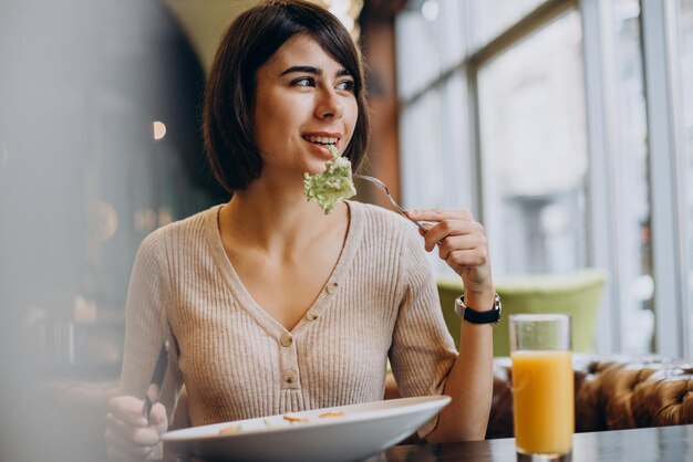 カフェでジュースと健康的な朝食を食べる若い女性