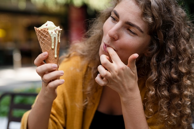 Giovane donna che mangia il cono gelato