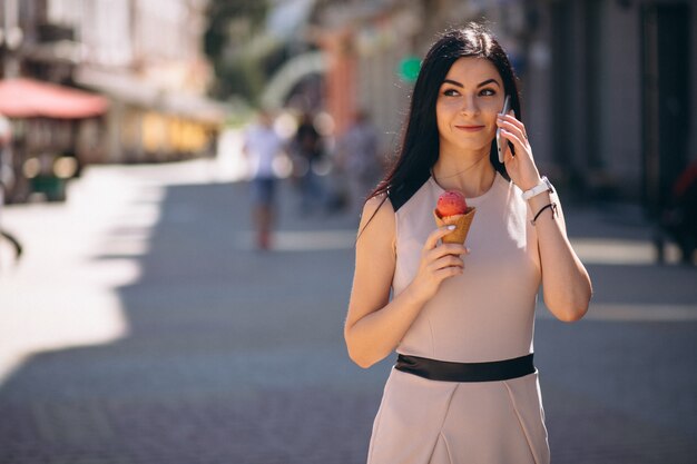 Молодая женщина, едят мороженое и говорить по телефону