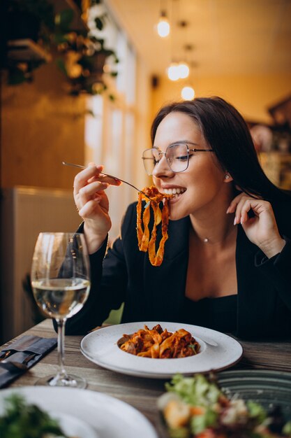 Молодая женщина ест макароны в кафе