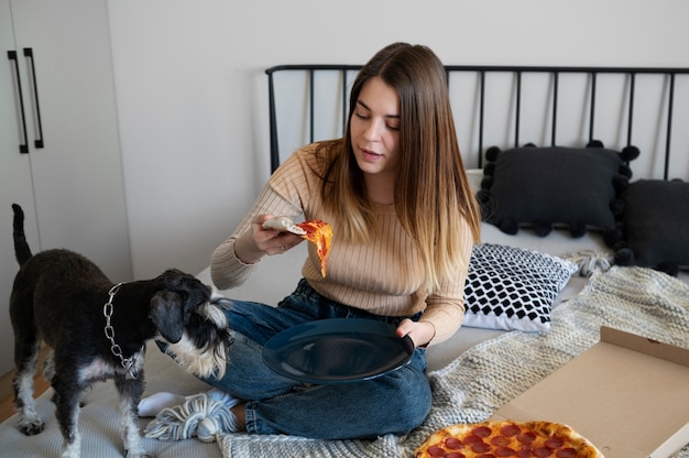 Young woman eating pizza on bed