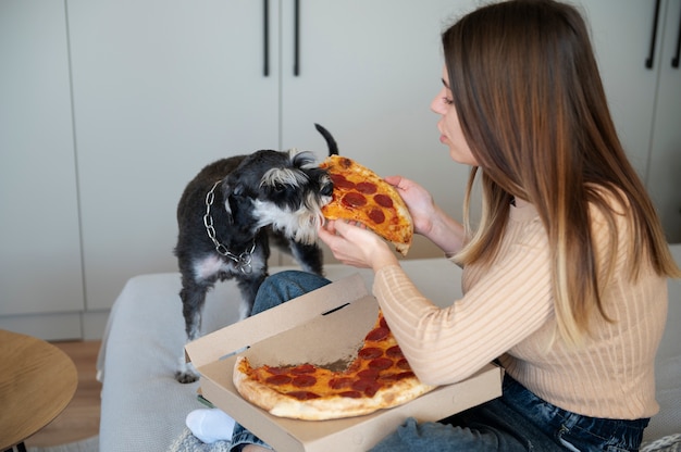 Giovane donna che mangia pizza sul letto