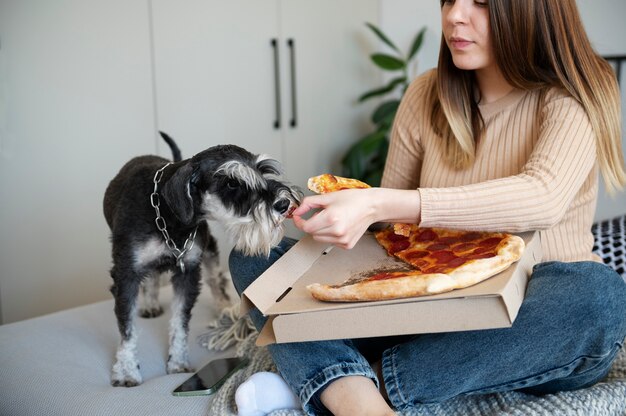 Young woman eating pizza on bed