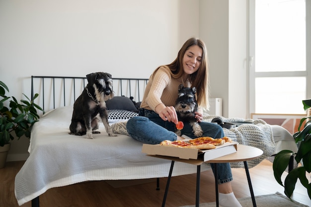 Young woman eating pizza on bed