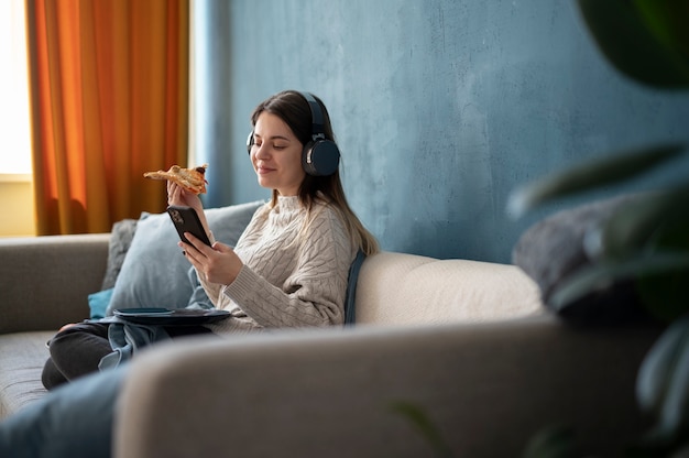 Free photo young woman eating pizza and listening to music