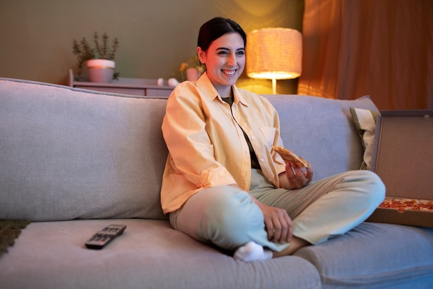 Young woman eating pizza and watching tv