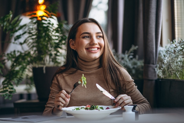 Молодая женщина ест салат в кафе