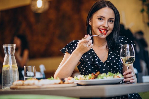 Free photo young woman eating salad in a cafe