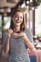 Free photo young woman eating strawberry cheesecake