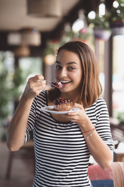 イチゴのチーズケーキを食べる若い女性