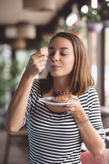 イチゴのチーズケーキを食べる若い女性