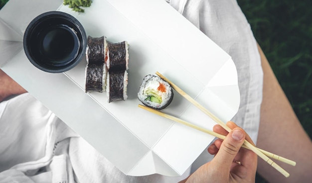 Free photo a young woman eating sushi in nature maki roll closeup