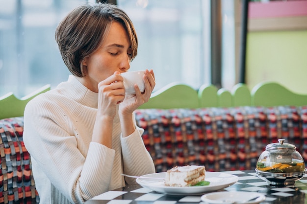 Young woman eating tiramisu with tea at a cafe