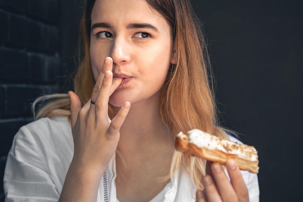 A young woman eats an appetizing eclair