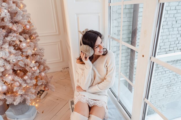 Young woman in an elegant dress near the Christmas tree