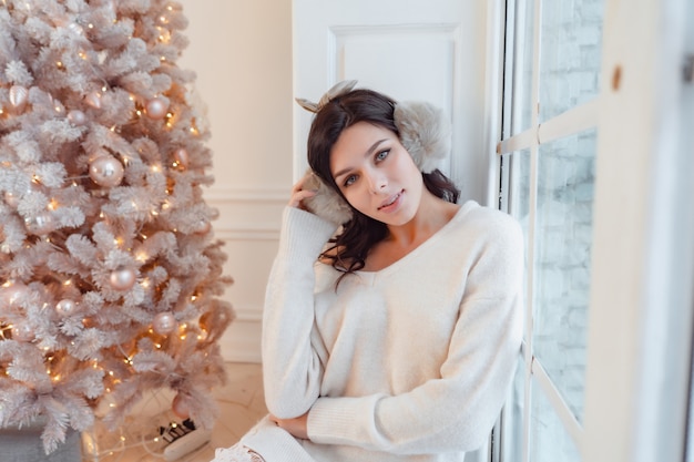 Young woman in an elegant dress near the Christmas tree