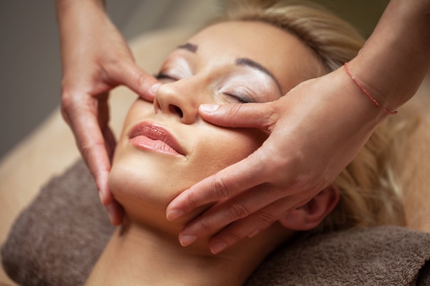 Young woman enjoy face massage in spa