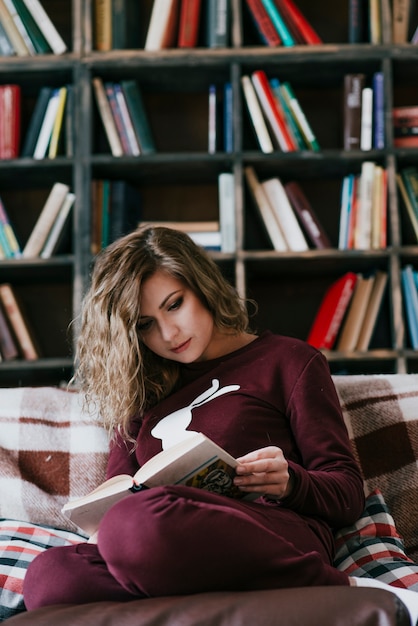 Free photo young woman enjoying reading on sofa