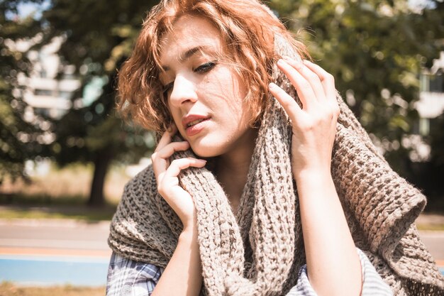 Young woman enjoying softness of scarf in park