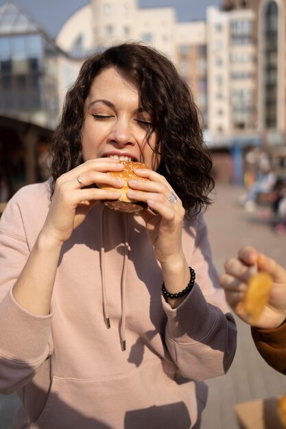 屋外で屋台の食べ物を楽しんでいる若い女性