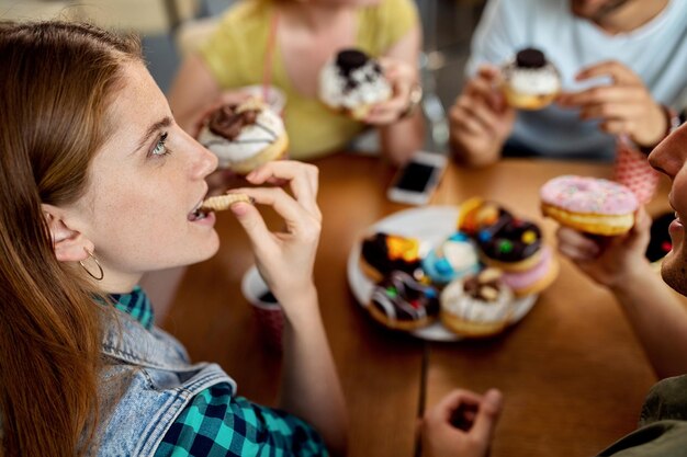 Молодая женщина наслаждается поеданием пончиков с друзьями