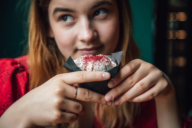 A young woman enjoys a raspberry muffin in a cafe