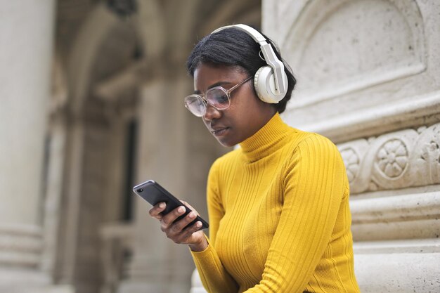 学校の入り口にいる若い女性が音楽を聴いています
