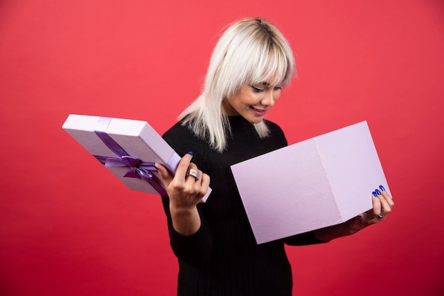 Young woman excited about a present on a red background