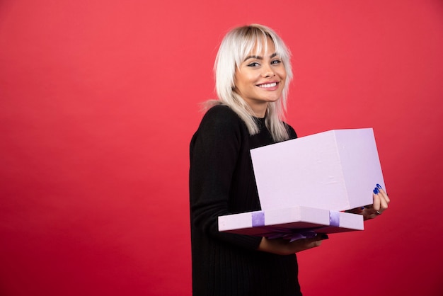 Free photo young woman excited about a present on a red background