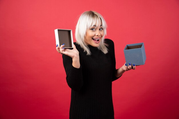 Young woman excited about a present on a red wall. 