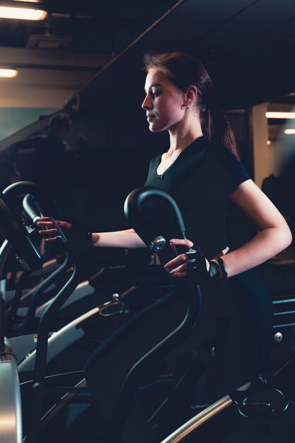 Young woman exercising on elliptical cardio machine