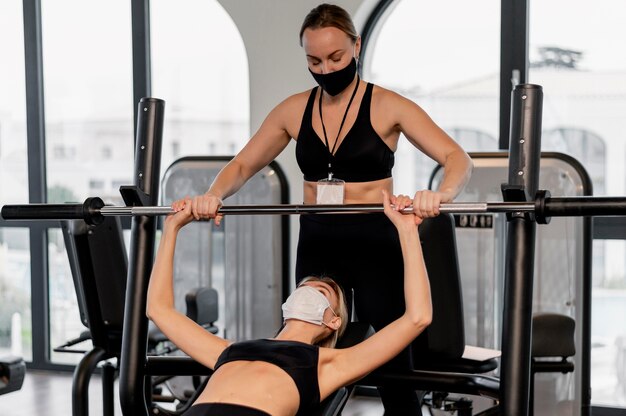 Young woman exercising at the gym and her coach