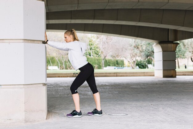 Young woman exercising near pillar