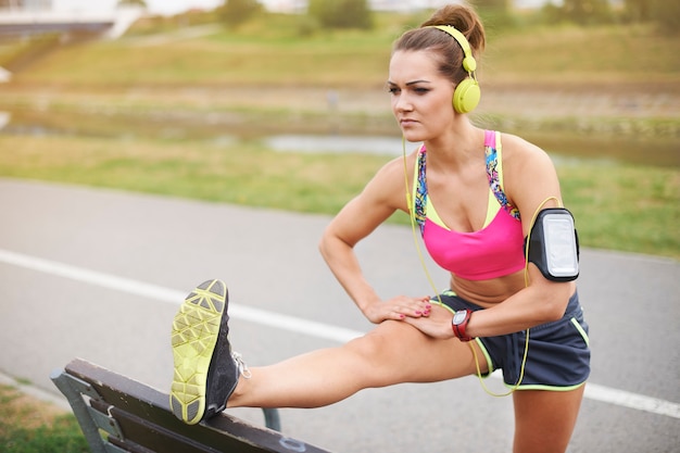 Young woman exercising outdoor. Focus woman stretching on the bench in the park