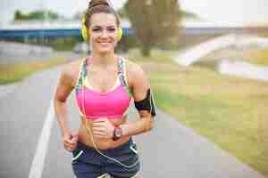 Free photo young woman exercising outdoor. good weather to go jogging by the river
