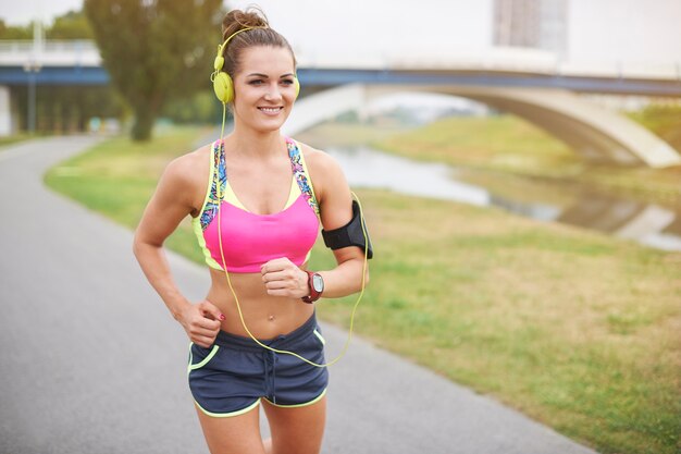 屋外で運動する若い女性。公園の川の上でジョギング