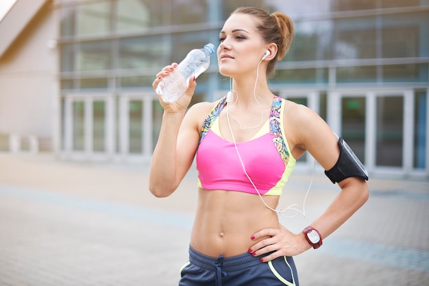 Young woman exercising outdoor. Our organism must be moisturized all the time