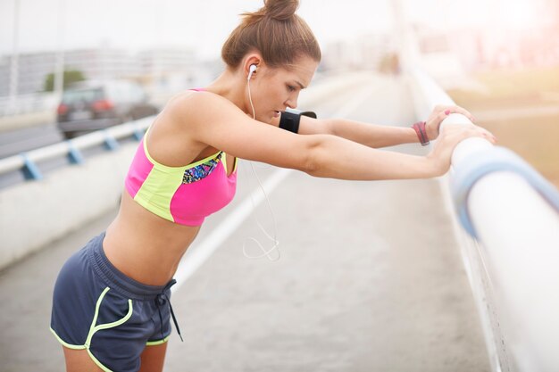 外で運動する若い女性。トレーニングの非常に重要な部分としてのストレッチ